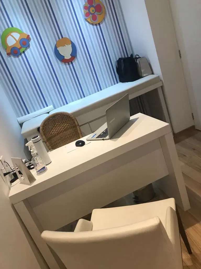 Sala de atendimento com mesa de trabalho e decoração infantil colorida