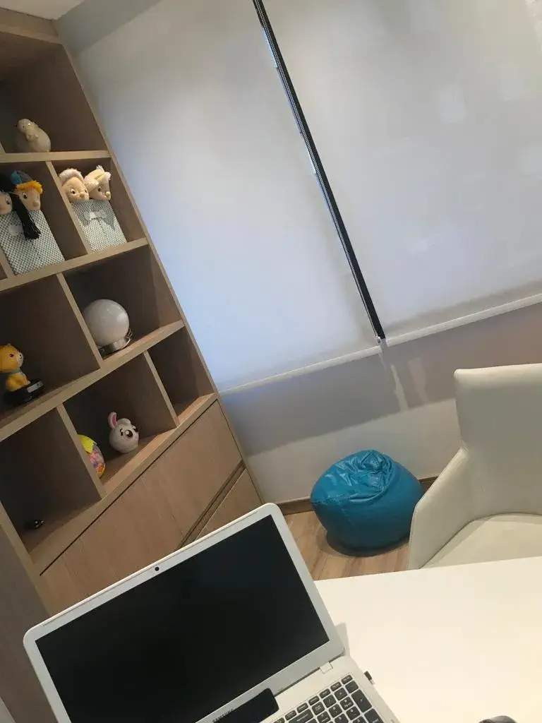 Consultório com estante de madeira, brinquedos e ambiente acolhedor