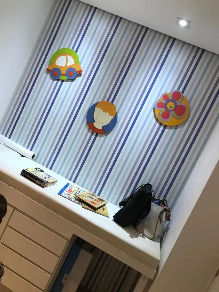 Parede decorada com papel de parede listrado e arte infantil colorida